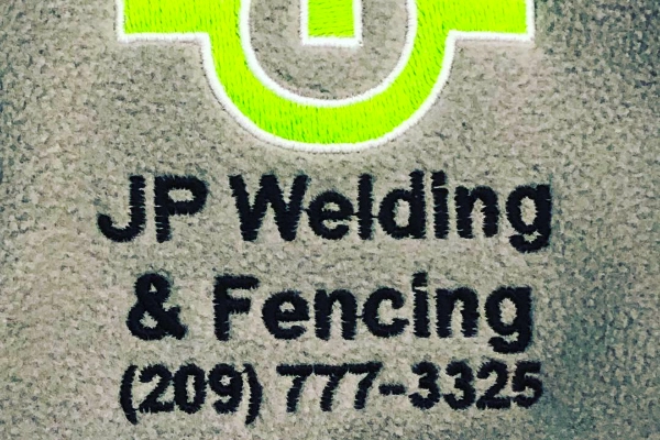 Embroidered JP Welding & Fencing company logo with phone number on a grey shirt